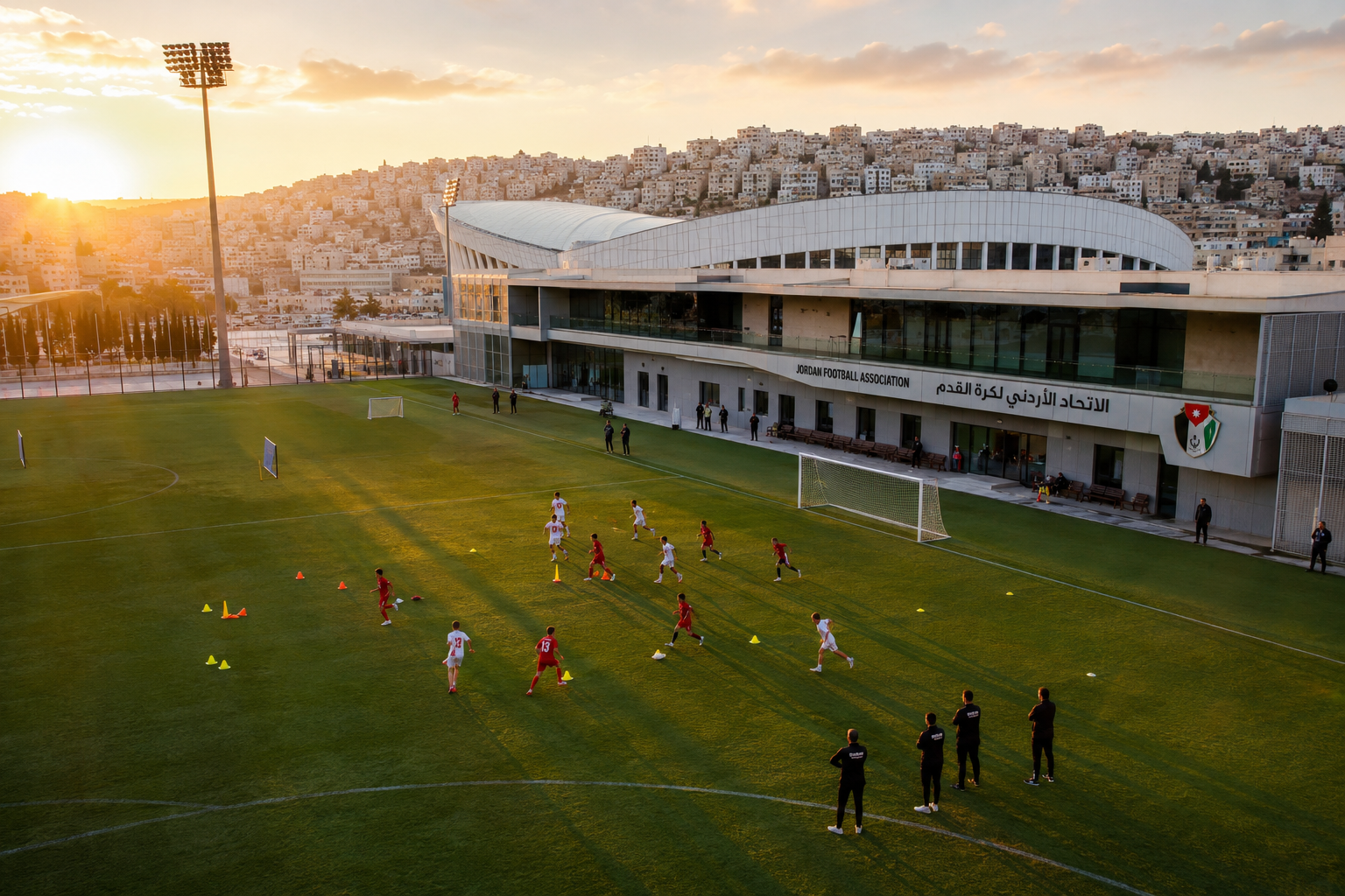() wide-angle aerial photograph of a modern football training facility in Amman Jordan, youth players in red and white
